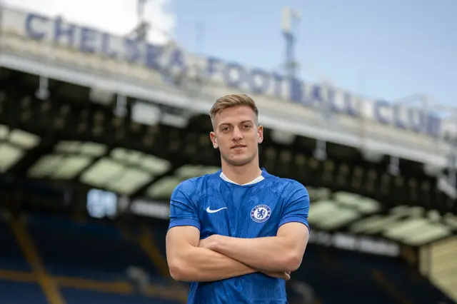 Liam Delap poses with arms folded after signing for Chelsea