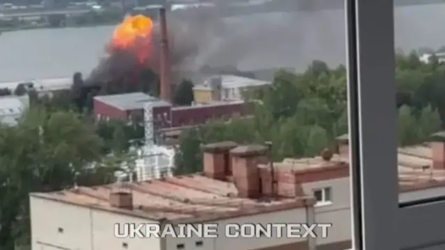 A large explosion is seen on the horizon over a building in Russia