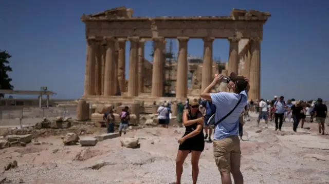 A tourist drinks water during his visit at the Parthenon temple atop the Acropolis hill, as a heatwave hits Athens, Greece, June 27, 2025.