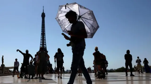 A tourist holding an umbrella to protect himself from the sun walks at Trocadero square next to the Eiffel Tower as an early summer heatwave hits Paris, France, July 1, 2025