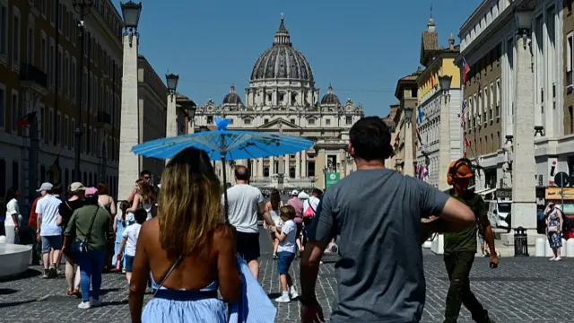 People walking near the Vatican on a hot day in Italy.