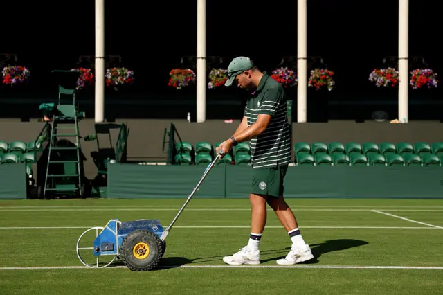 A man rolling white paint on the grass at Wimbledon