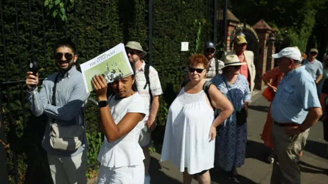 Wimbledon spectators take cover using newspaper and use portable fans to cool down amid the heatwave on day two of the tournament