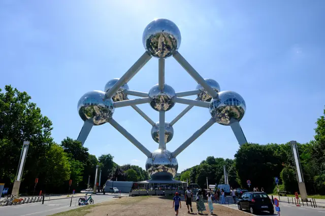 Tourists look to find shadow under The Atomium during a heatwave, on July 1, 2025 in Brussels, Belgium