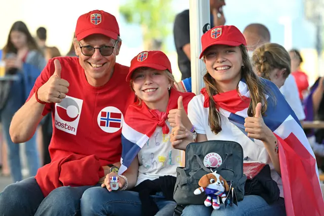 Norway fans pose outside the stadium wearing their country's colours