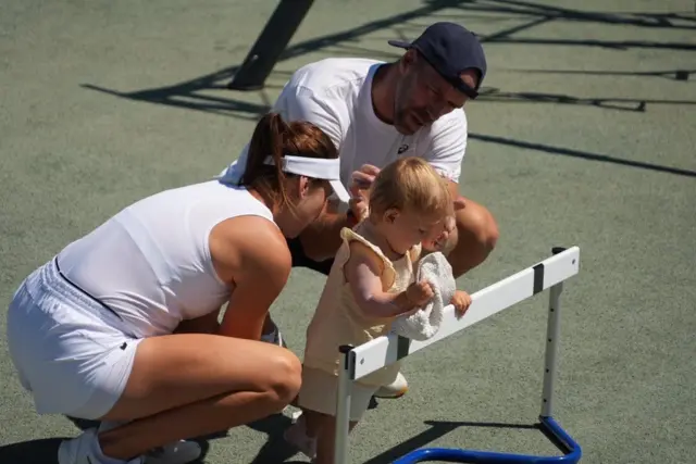 Belinda Bencic's daughter Bella with her parents in the practice area at Wimbledon