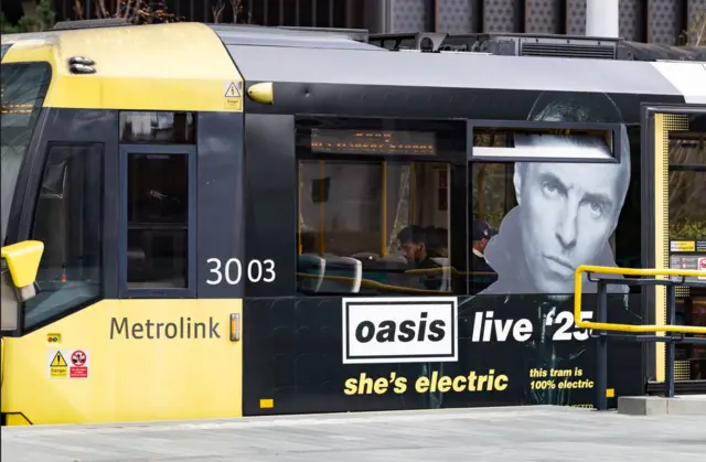 A Metrolink tram with Liam Gallager's face on the outside advertising Oasis's tour with the words 'She's electric'