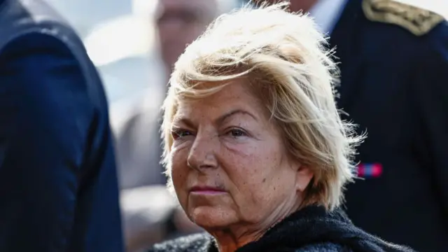 Close-up of Mayor of Calais Natacha Bouchart (middle-aged woman, short blonde hair) attends an event outside, wind moving her hair to the left