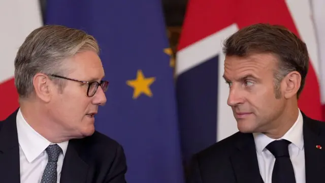 Starmer speaking and turned to face Macron, who looks into Starmer's eyes