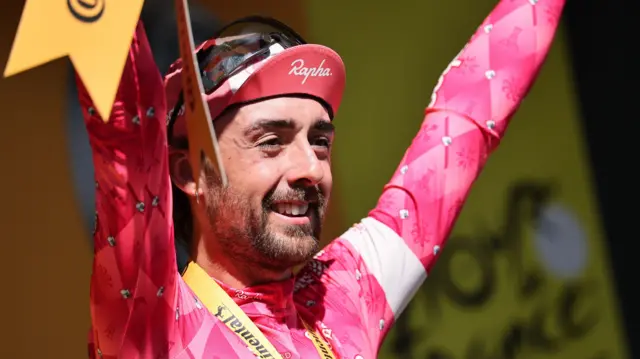 Ben Healy with his arms aloft on the podium after winning stage six of the 2025 Tour de France