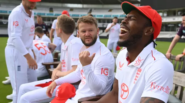 Jofra Archer, sat on a bench during a photocall, laughs while team-mate Ben Duckett looks on