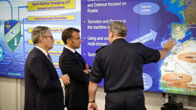 Starmer and Macron speak to a NATO military officer who points to a screen of a world map setting out global threats.