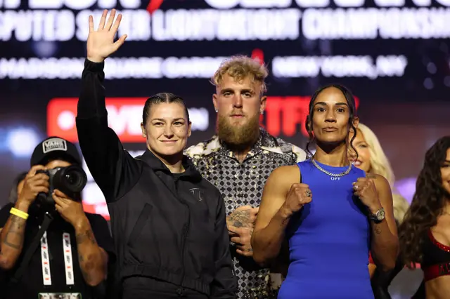 Katie Taylor waving next to Jake Paul and Amanda Serrano