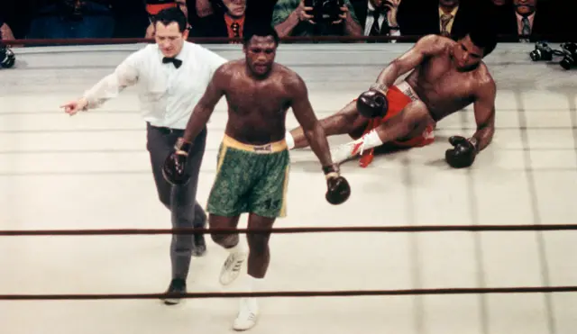 Muhammed Ali on the canvas with Joe Frazier walking back to the corner