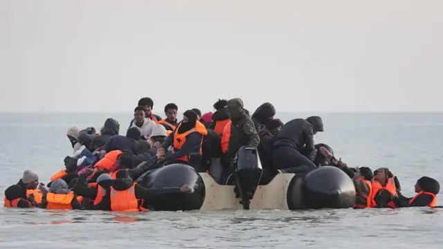 People thought to be migrants scramble onboard a small boat leaving the beach at Gravelines, France, in an attempt to reach the UK by crossing the English Channel.
