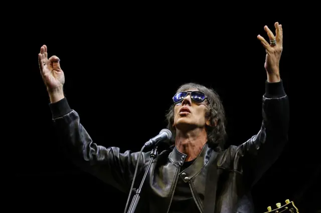 Richard Ashcroft with his arms aloft.