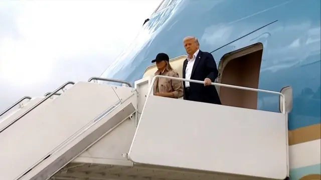Donald Trump and Melania Trump standing at top of steps coming off Air Force One