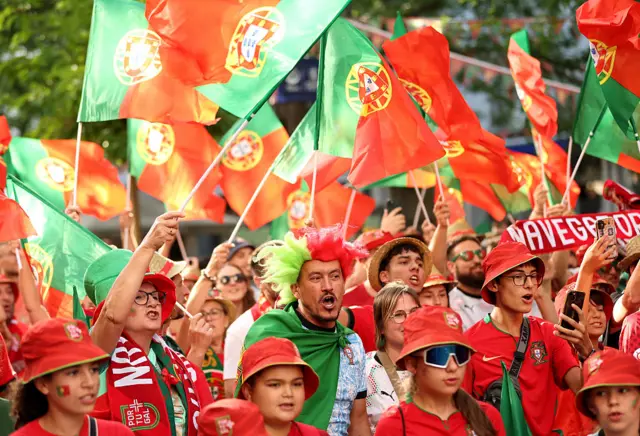 Portugal fans wave flags and sing as they make their way to the stadium
