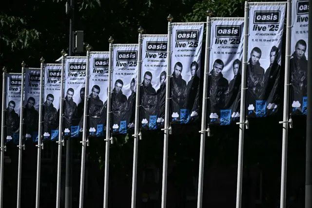 Numerous flags showing a black and white picture of Liam and Noel Gallagher and details of Oasis's tour