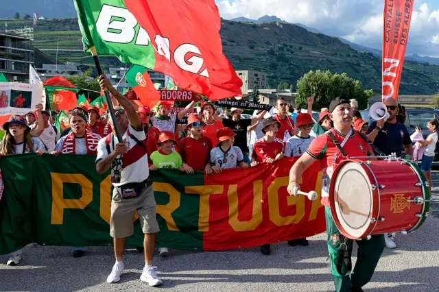 Portugal fans chant and wave flags and bang drums as they march to the stadium