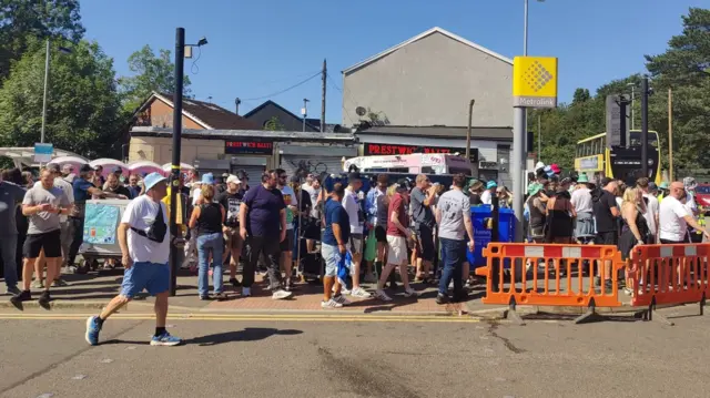 A crowd of people gathered outside Heaton Park tram stop