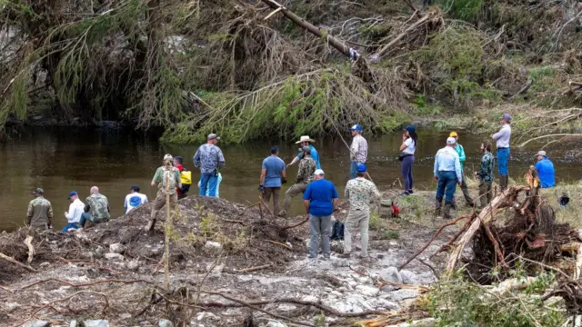 Members of a search and rescue team look for missing people amid debris in the waters of the Guadalupe River