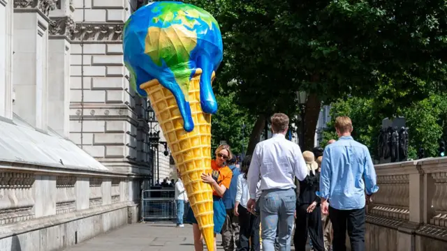 A member of the Mothers Rise Up group carry a giant melting planet ice cream cone outside of Downing Street in amongst the crowds on July 09, 2025 in London, England.