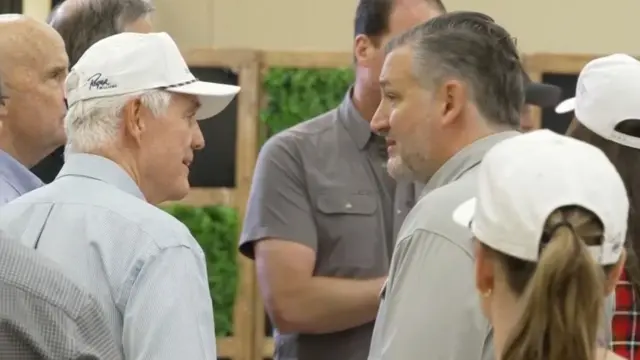 Two men, including Ted Cruz, standing and chatting amid group