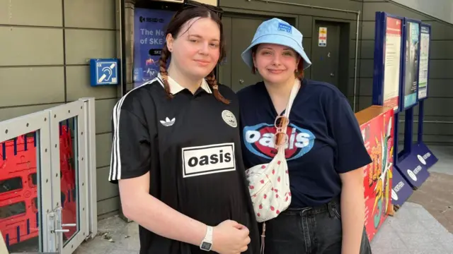 Noah Jenrich and Maddisyn Wherlock, are both wearing Oasis T-shirts as they pose for a photograph at Victoria railway station