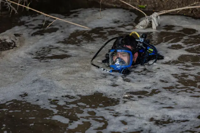 A rescue diver searches through debris in the Guadalupe River for missing people on 10 July