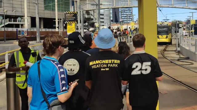 A line of people queuing for the tram to Heaton Park.
