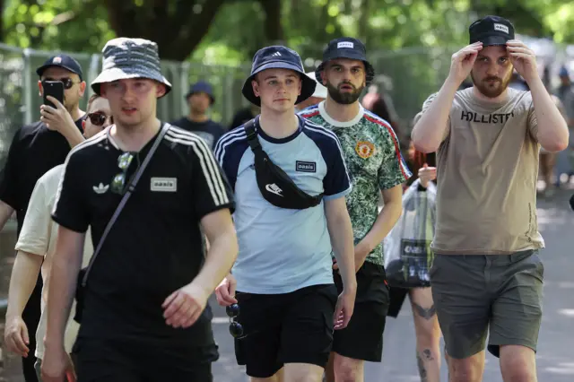 Four men wearing bucket hats and T-shirts walk towards the camera