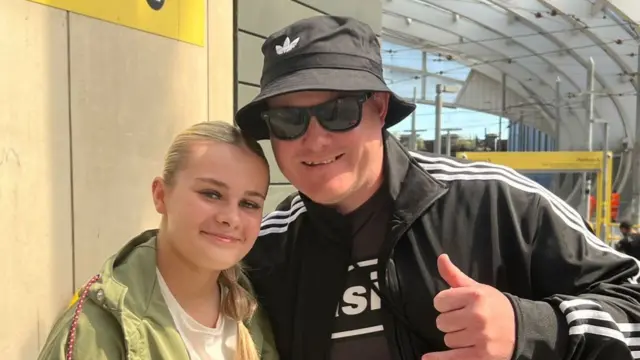 The father and daughter are smiling for a photograph at Victoria railway station.