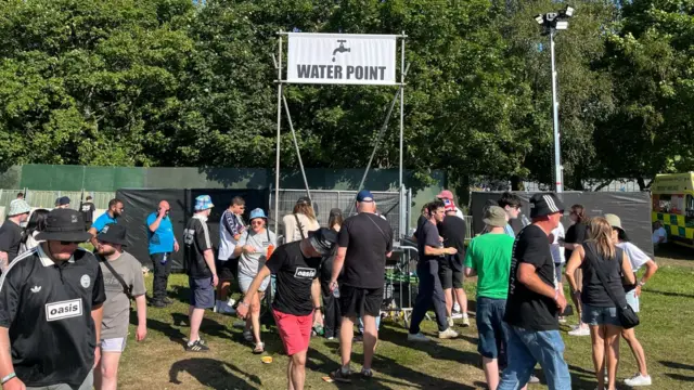 A wide shot of the water point where people can get a drink.
