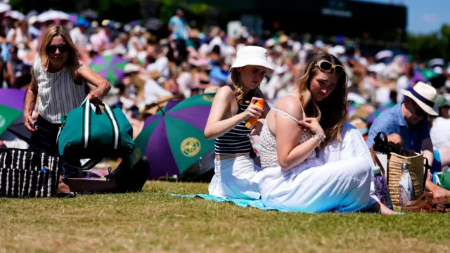 Spectators apply suncream