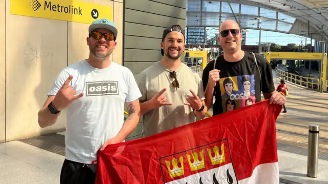 The three fans are all posing for a photograph at Victoria railway station.