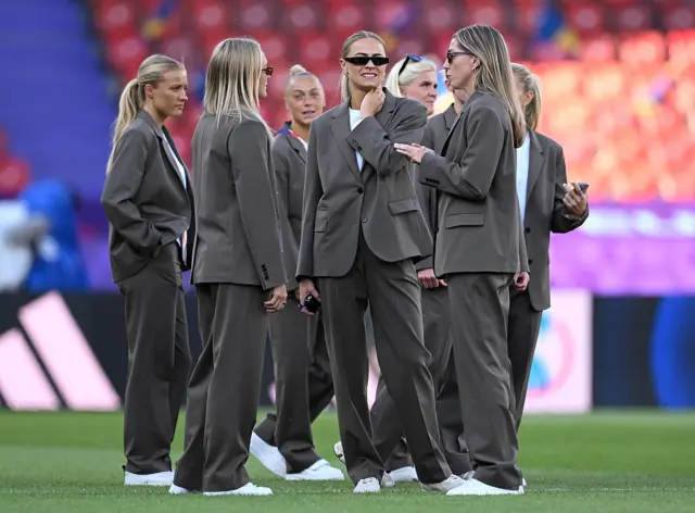 Sweden players stand on the pitch in their brown suits and white t shirts