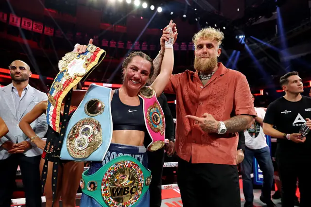 Ellie Scotney with all her world titles, her hand being held up by Jake Paul