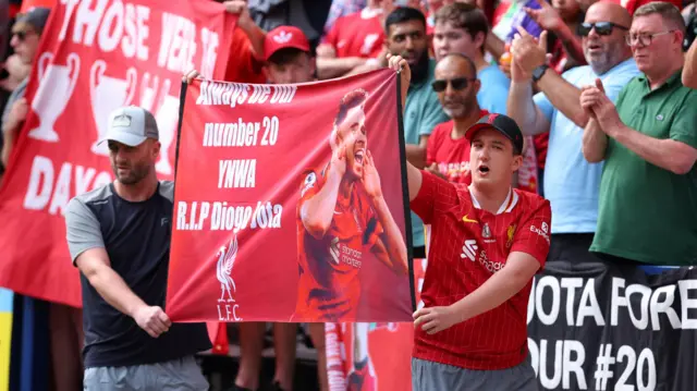 Liverpool fans walk in front of the away fans with a poster in Diogo Jota's honour