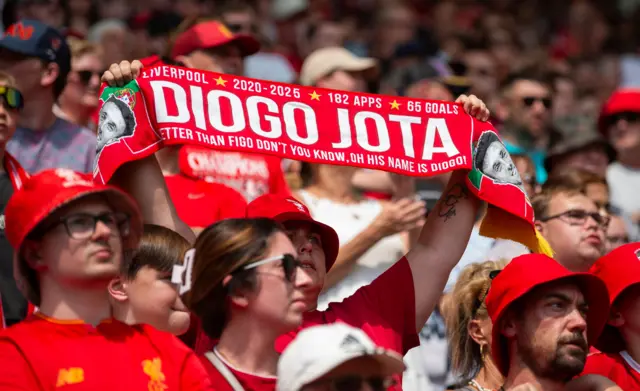 A Liverpool fan with a scarf in honour of Diogo Jota