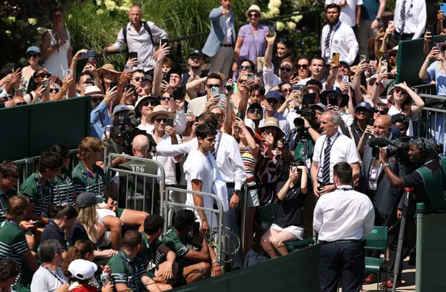 Carlos Alcaraz surrounded by fans as he arrives at court 14 Wimbledon