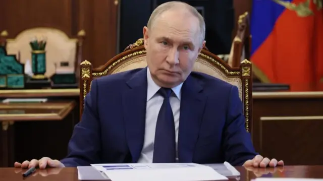 Vladimir Putin sitting at a desk, with paperwork in front of him
