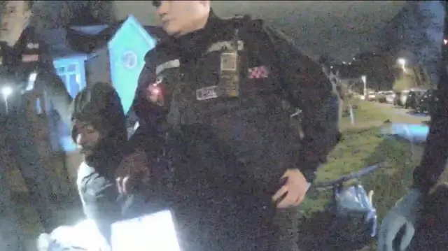 Police bodycam image shows an officer with his hand on Mark Gordon's shoulder - they're outside in the dark, lit by streetlamps and police torches