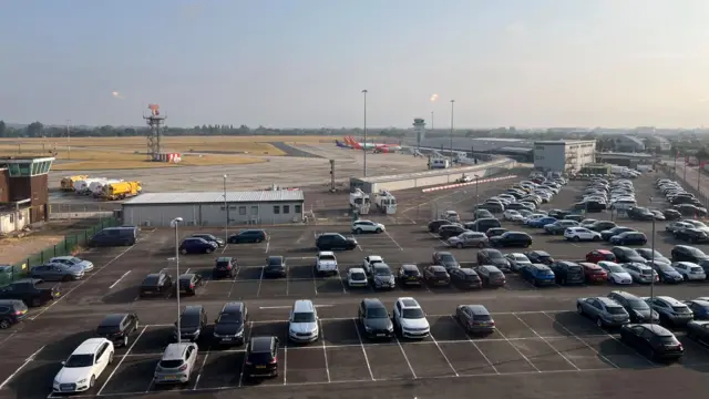 Aerial view of Southend Airport. There are lots of cars in the car park and three EasyJet planes are visible next to the terminal building.