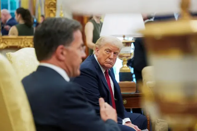 A side view of Trump looking over to Rutte speaking in the Oval Office
