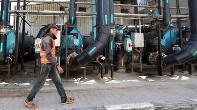 A Palestinian man walks past one of the strip's desalination plants on 10 March 2025