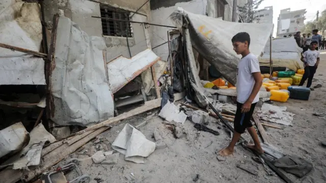 A Palestinian boy inspects the site of an Israeli strike that killed Palestinians, gathered to collect water from a distribution point, according to medics, in Nuseirat in the central Gaza Strip