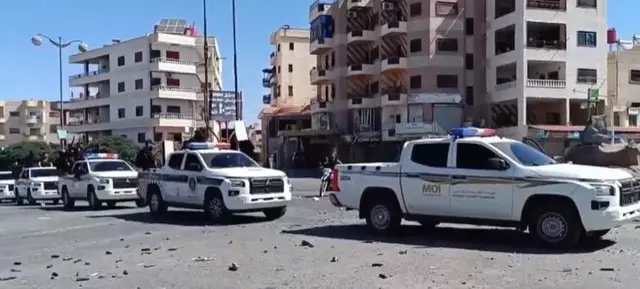 Screengrab showing a convoy of marked pickup trucks carrying armed men
