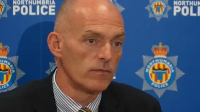 Calum Meikle looking to the right of the camera. He is sitting in front of a blue Northumbria Police background.