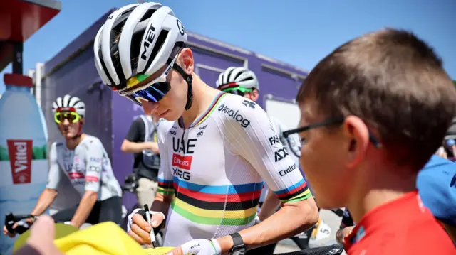 Tadej Pogacar signing a jersey before stage 11 of the 2025 Tour de France